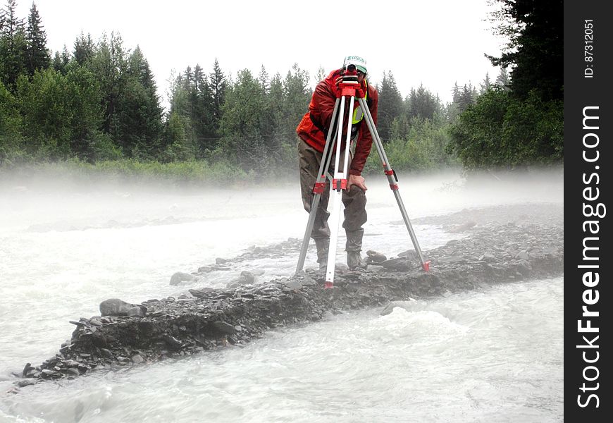 Using Science to Improve Infrastructure â€” In this photo, we see Paul Schauer &#x28;USGS&#x29; running a level survey for the streambed scour project in Seward, Alaska. The goal of this type of work is to evaluate the scour susceptibility of bridges in order to identify structures that require mitigation of the scour problem, annual monitoring, or near real-time scour monitoring. Bridge scour isâ€‹ basicallyâ€‹ the removal of sediment &#x28;like rock, sand, etc&#x29; from around the bridge causing it to weaken. Streambed scour at bridges is the leading cause of bridge failure in the United States. The costs associated with restoring damaged structures are substantial, but the indirect costs associated with the disruption of traffic can be up to five times greater. These costs and the societal repercussions are even greater in Alaska, where alternate land routes between many cities do not exist. Flood damage to two bridges on the George Parks Highway between Anchorage and Fairbanks closed the highway for four days in August 2006 and repair costs to these structures and others damaged during the flooding are estimated at over 13 million dollars. Learn more about this project at bit.ly/AKScour.