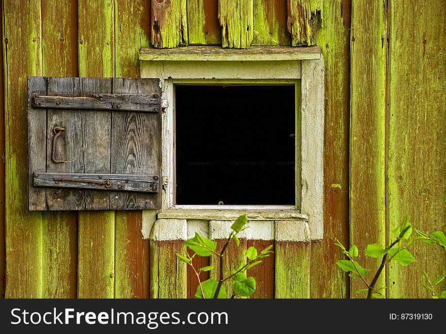 Closeup of old wooden building with small window and rough shutter (hinged door) to fit the opening during inclement weather. Closeup of old wooden building with small window and rough shutter (hinged door) to fit the opening during inclement weather.