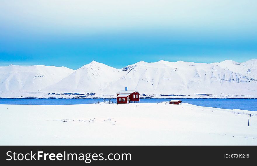 A red cabin in the middle of white snow fields. A red cabin in the middle of white snow fields.