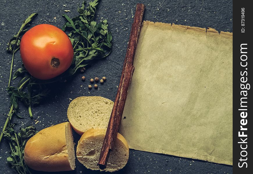 A rustic background with tomato, bread, herbs and an old parchment paper. A rustic background with tomato, bread, herbs and an old parchment paper.