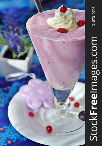 Strawberry milkshake in tall glass with berries and vanilla ice cream.