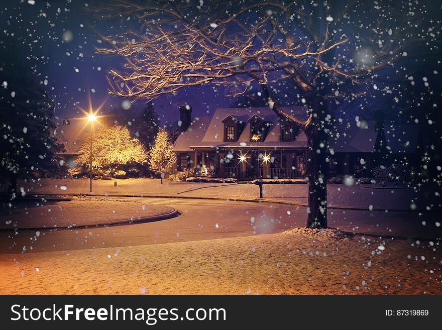 A residential house in snowy weather at night.