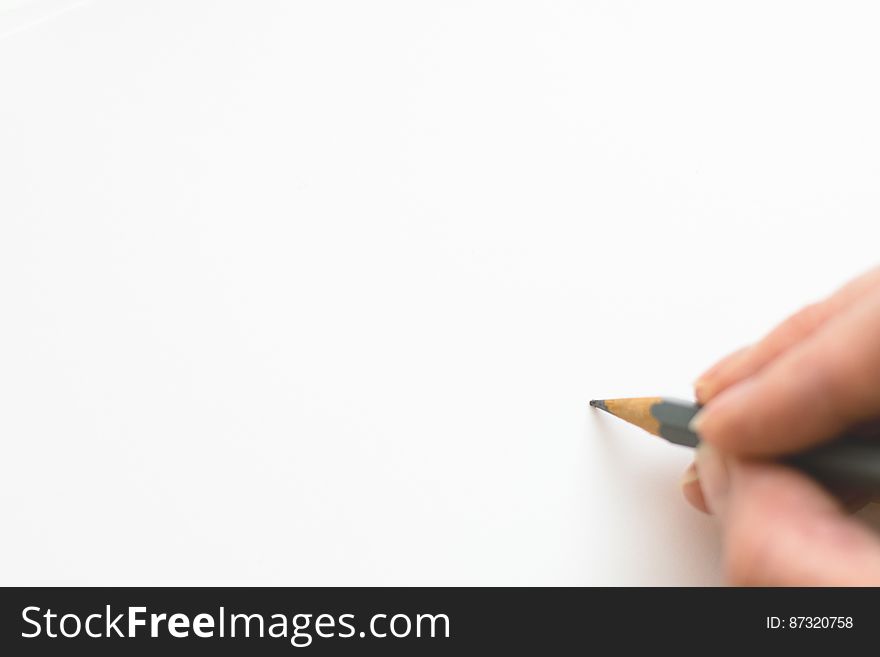 Close-up Of Hand Holding Pencil Over White Background