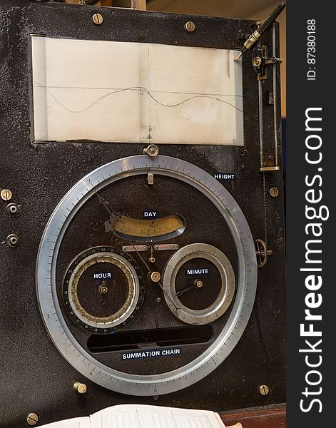 The output face of Tide Predicting Machine No. 2, a special purpose mechanical analog computer for predicting the height and time of high and low tides. The pen at the top draws the tide height as the paper moves beneath it. The dials below display the predicted tide height and the corresponding date and time. When the machine was in operation, the operator recorded the height and time of high and low tides, which were later reproduced in printed tide tables. The U.S. government used Tide Predicting Machine No. 2 from 1910 to 1965 to predict tides for ports around the world. The machine, also known as â€œOld Brass Brains,â€ uses an intricate arrangement of gears, pulleys, chains, slides, and other mechanical components to perform the computations. A person using the machine would require 2-3 days to compute a yearâ€™s tides at one location. A person performing the same calculations by hand would require hundreds of days to perform the work. The machine is 10.8 feet &#x28;3.3 m&#x29; long, 6.2 feet &#x28;1.9 m&#x29; high, and 2.0 feet &#x28;0.61 m&#x29; wide and weighs approximately 2,500 pounds &#x28;1134 kg&#x29;. The operator powers the machine with a hand crank.