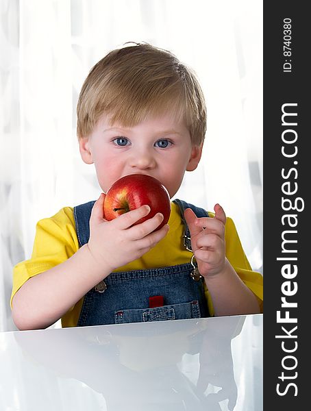 The little boy holds an apple in hands. The little boy holds an apple in hands