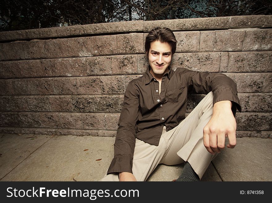 Young man resting on a wall and smiling. Young man resting on a wall and smiling