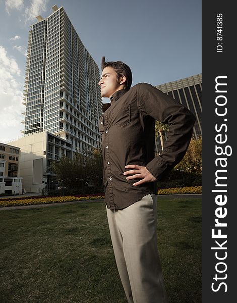 Man standing in a field of grass with a modern building in the background. Man standing in a field of grass with a modern building in the background