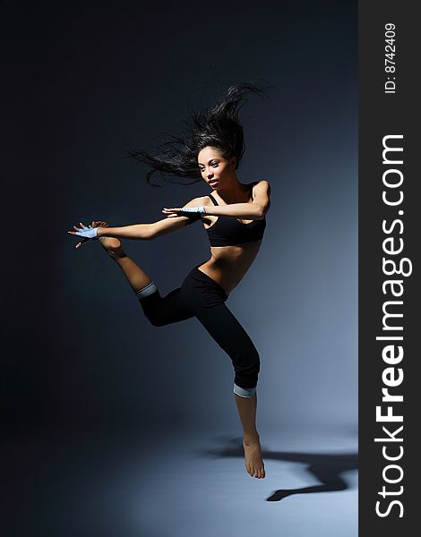 Modern style dancer posing behind studio background