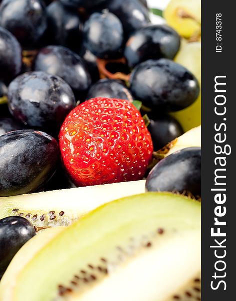 Assorted fresh fruits background including strawberry, apple, kiwi and black and green grape