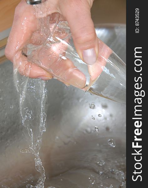 Hand washing wineglass in water in sink. Hand washing wineglass in water in sink