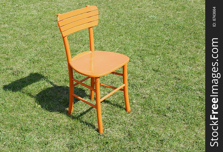 Orange wooden chair on green grass outdoor. Orange wooden chair on green grass outdoor