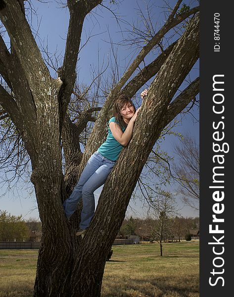 A beautiful teen girl peers down from her perch in a tree. A beautiful teen girl peers down from her perch in a tree.