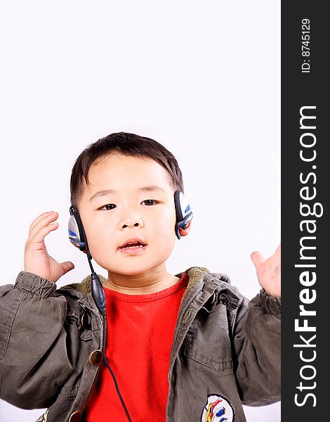 A picture of a little chinese boy listening to music with earphone, having great fun. A picture of a little chinese boy listening to music with earphone, having great fun