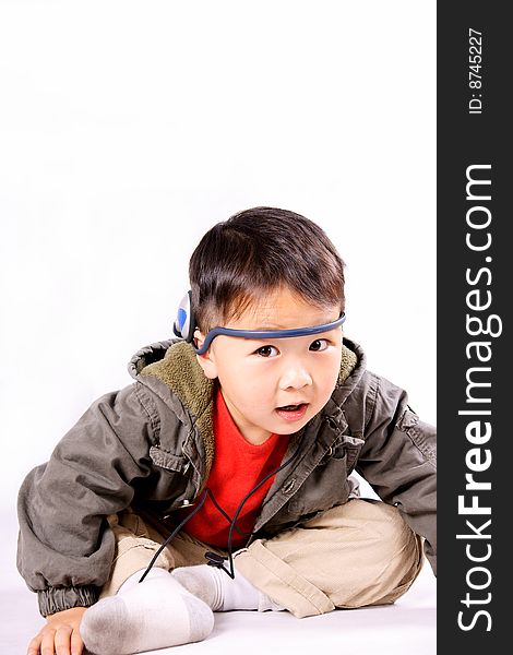 A picture of a little chinese boy listening to music with earphone, having great fun. A picture of a little chinese boy listening to music with earphone, having great fun