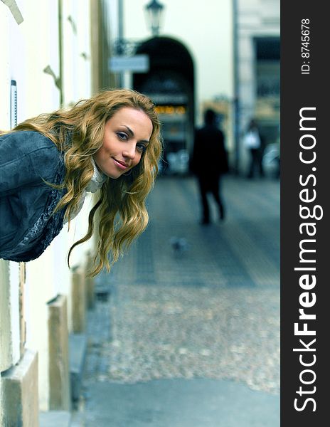 The woman in the street looks out of an arch and smiling