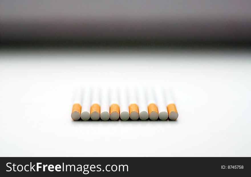 Cigarettes lie on a white background in a row
