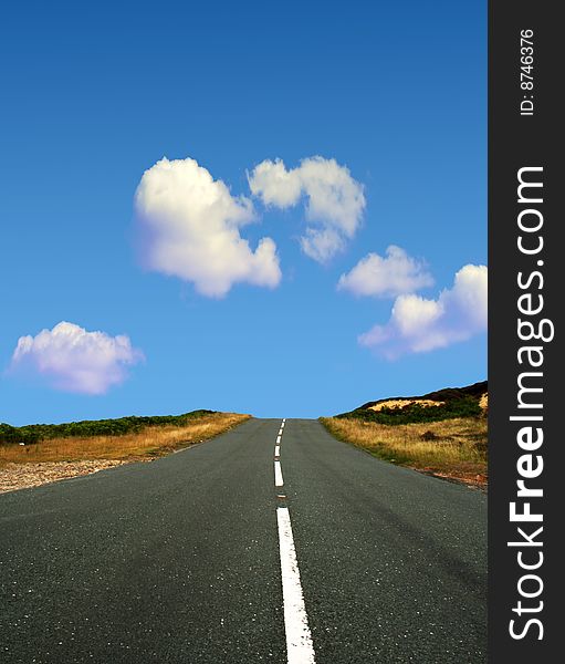 Country road leads towards blue cloudy sky