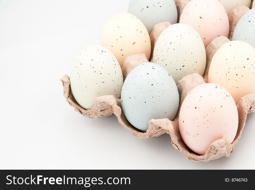 Pastel colored Easter eggs in crate on white background.