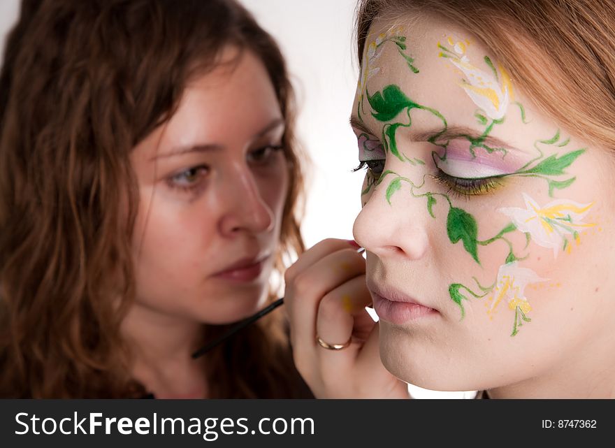 An artist making the flower tattoo on the face of