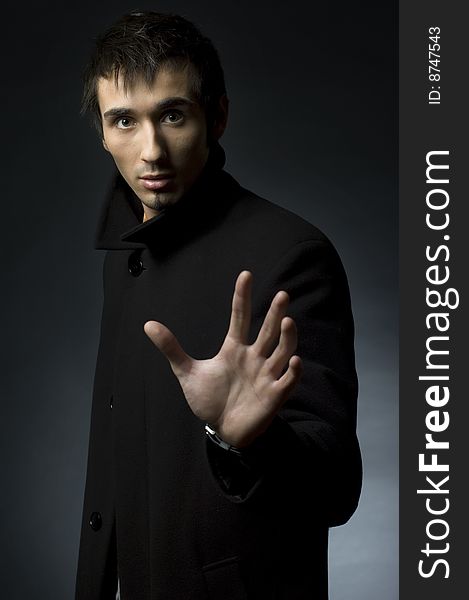 Portrait of a young business man with his hands on a dark background. Portrait of a young business man with his hands on a dark background