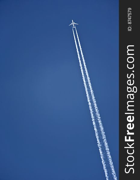 The airplane flies across the blue sky