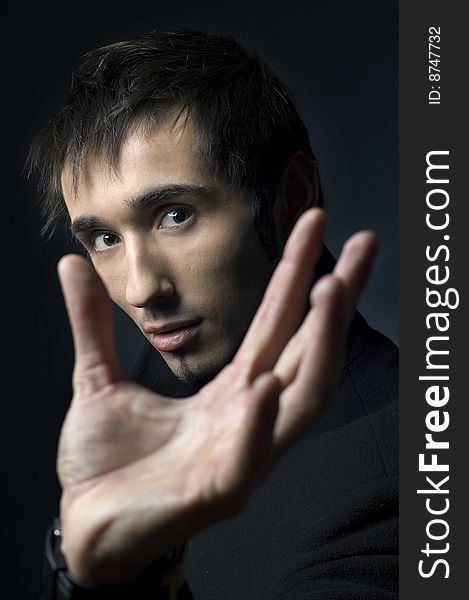 Portrait of a young business man with his hands on a dark background. Portrait of a young business man with his hands on a dark background