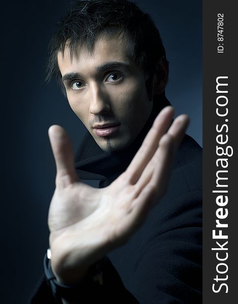 Portrait of a young business man with his hands on a dark background. Portrait of a young business man with his hands on a dark background