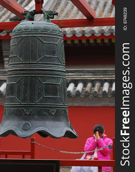 A young girl was praying toward a grand bell.