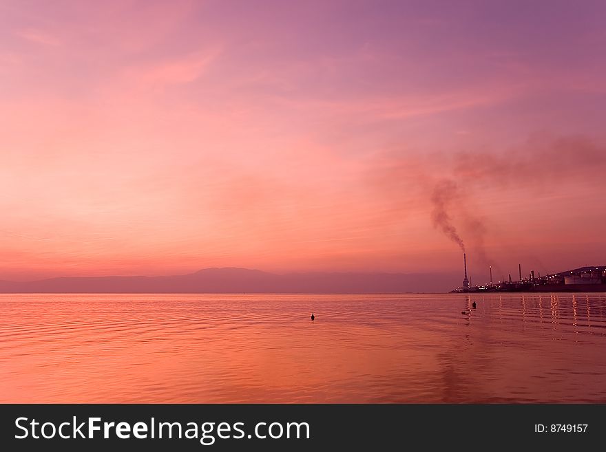 Purple sunset over sea water with industrial plant a side. Purple sunset over sea water with industrial plant a side