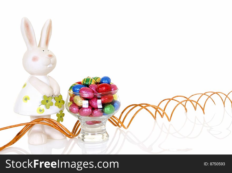 Colorful wrapped chocolate Easter eggs on white background, reflective surface