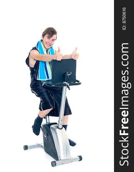 Young teenager boy doing fitness on hometrainer with laptop studying,. Young teenager boy doing fitness on hometrainer with laptop studying,