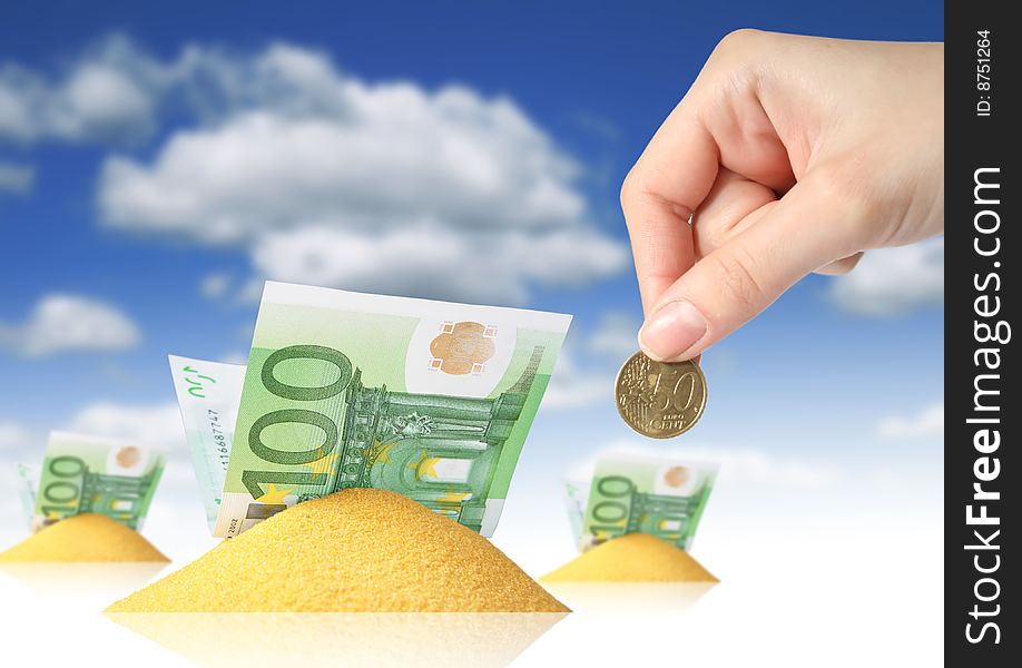 Financial concept. Hand, sand and money over blue sky background.