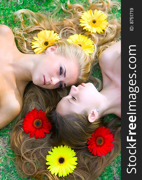 Two girls lying on grass with flowers in their hair. Two girls lying on grass with flowers in their hair