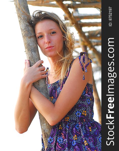 Beautiful smiling young blond girl on the beach holding a pole. Beautiful smiling young blond girl on the beach holding a pole