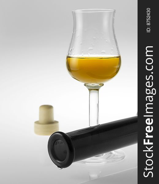 A liqueur glass with bottle on reflective background. A liqueur glass with bottle on reflective background