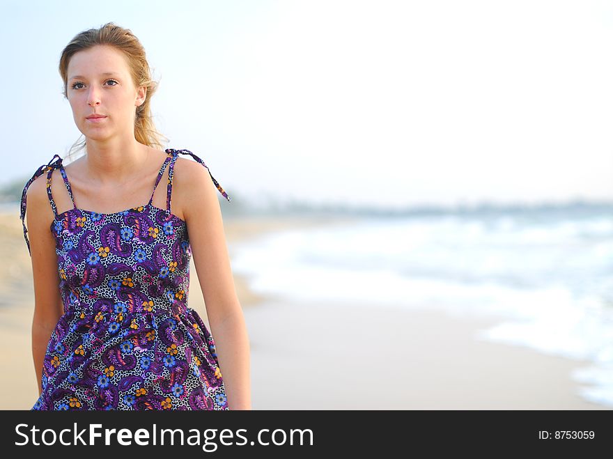 Beautiful young blond girl walking in the water on the beach. Beautiful young blond girl walking in the water on the beach