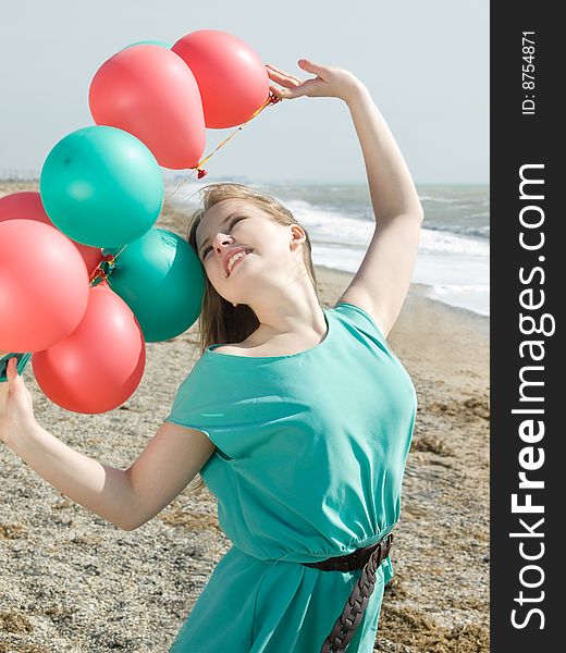 Emotional girl with balloons on the sea shore