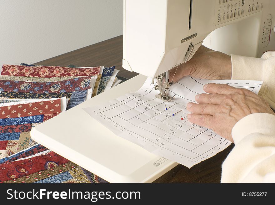 A quilter sews paper pieced log cabin quilt pattern. A quilter sews paper pieced log cabin quilt pattern.