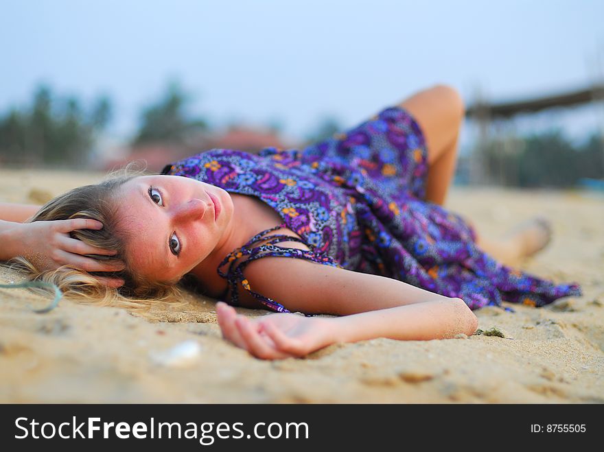 Young attractive girl laying on the beach looking into the camera. Young attractive girl laying on the beach looking into the camera