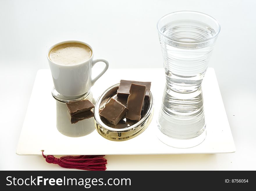 Coffee, chocolate and cup of water on a plat