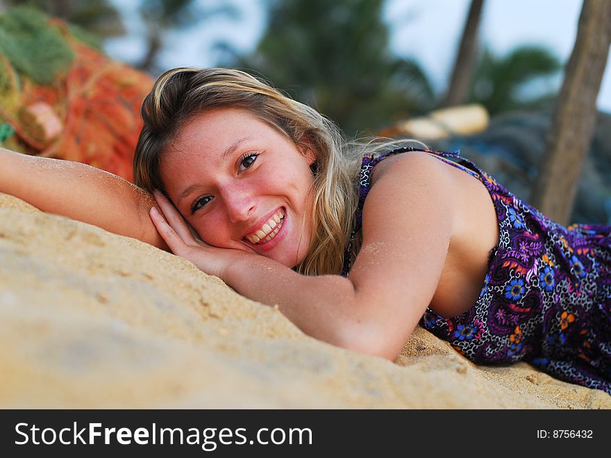 Young attractive smiling girl laying on the beach looking into the camera. Young attractive smiling girl laying on the beach looking into the camera