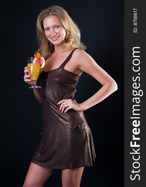 Beautiful girl in a brilliant dress with a cocktail against a dark background. Beautiful girl in a brilliant dress with a cocktail against a dark background