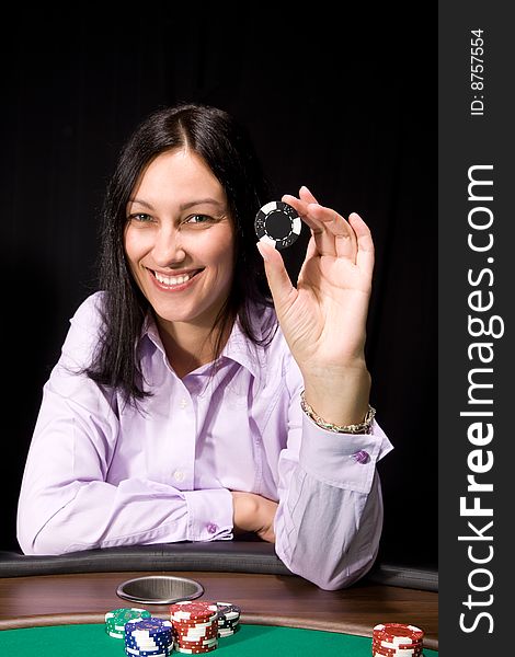 Smiling girl shows casino chip over black