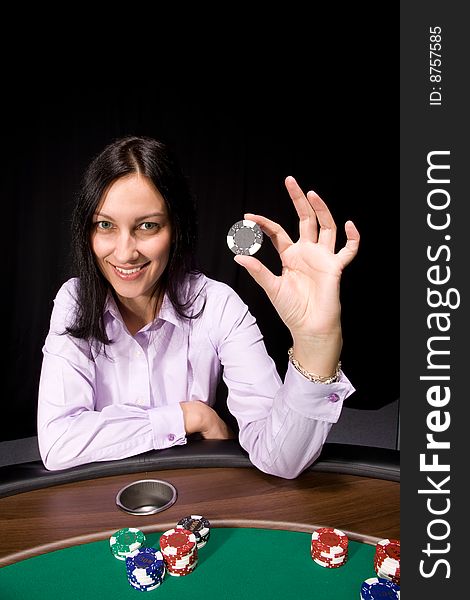 Pretty caucasian girl holds casino chip in hand over black