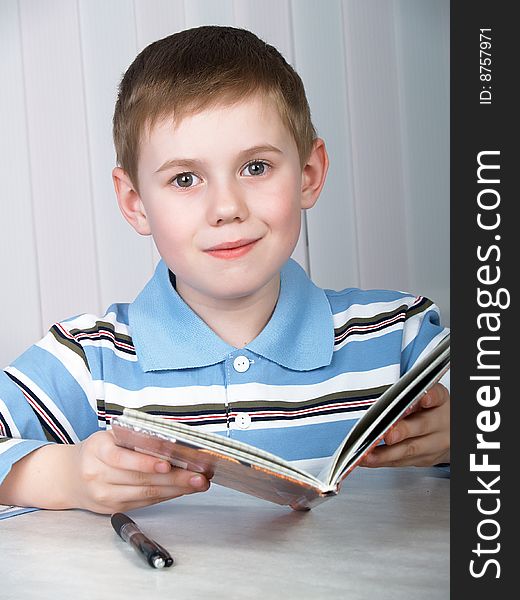 The litle boy doing homework on the table. The litle boy doing homework on the table