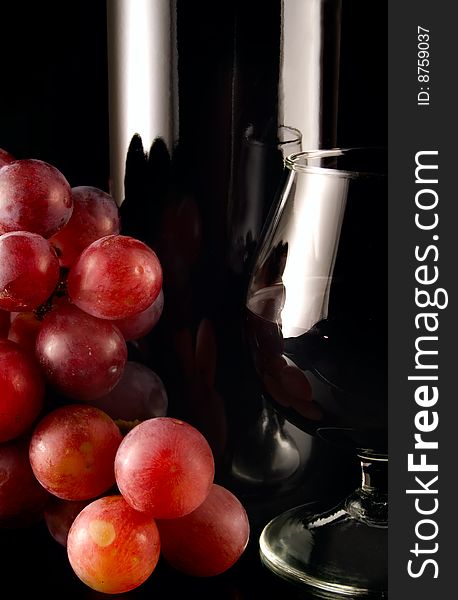 Red grape and bottle of wine on black background with reflection. Red grape and bottle of wine on black background with reflection