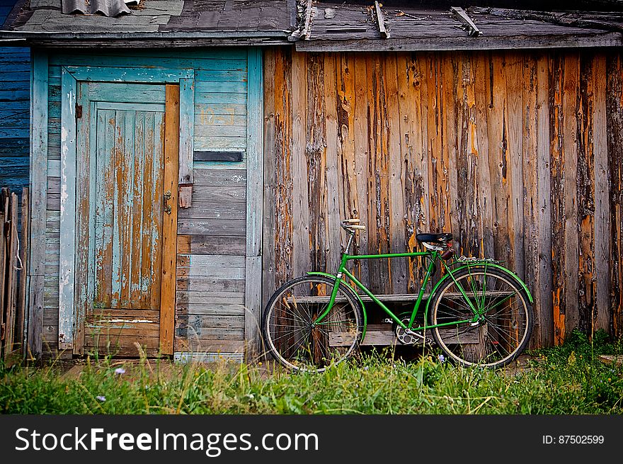 Green Bicycle By Wooden Building