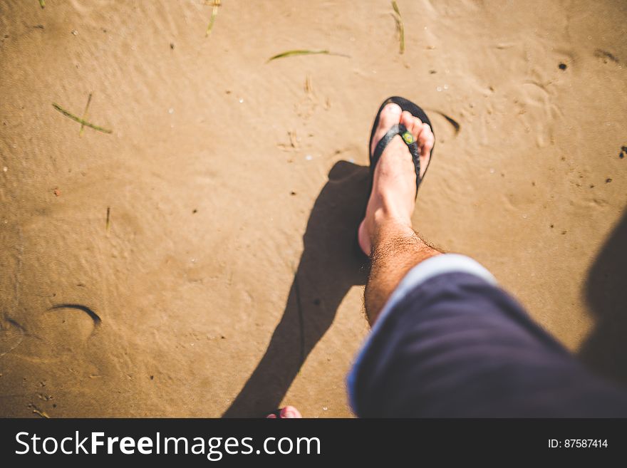 Man wearing open sandals (slipper or flip flops) putting one foot onto the almost pristine beach. Man wearing open sandals (slipper or flip flops) putting one foot onto the almost pristine beach.