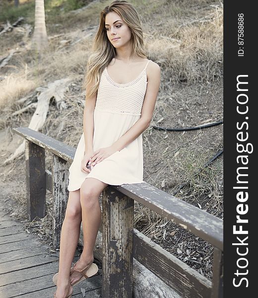 A woman sitting on a wooden railing. A woman sitting on a wooden railing.