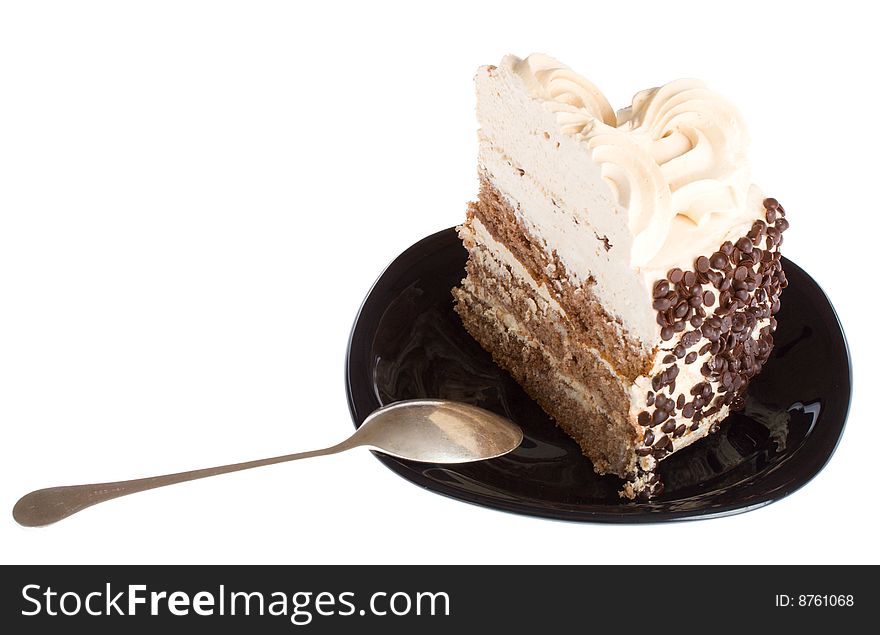 Close-up piece of cake and spoon on black plate, isolated